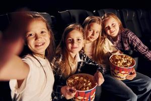 seduta su il nero sedili. gruppo di bambini seduta nel cinema e Guardando film insieme foto