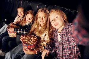 nel buio camera. gruppo di bambini seduta nel cinema e Guardando film insieme foto