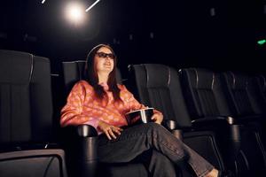 adulto donna seduta nel il cinema e Guardando film foto