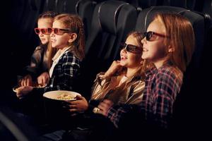 delizioso Popcorn. gruppo di bambini seduta nel cinema e Guardando film insieme foto