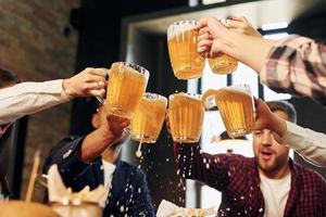 avendo conversazione. gruppo di giovane amici seduta insieme nel bar con birra foto