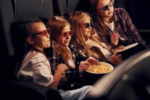 fine settimana divertimento. gruppo di bambini seduta nel cinema e Guardando film insieme foto