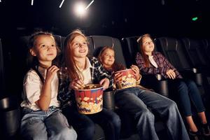 rilassante e avendo divertimento. gruppo di bambini seduta nel cinema e Guardando film insieme foto