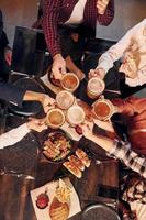allegro emozioni. gruppo di giovane amici seduta insieme nel bar con birra foto