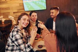 parlando con ogni Altro. gruppo di giovane amici seduta insieme nel bar con birra foto