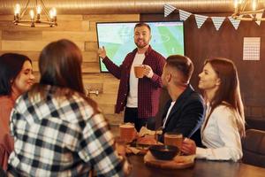 positivo facciale espressione. gruppo di giovane amici seduta insieme nel bar con birra foto