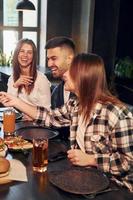 positivo emozioni. gruppo di giovane amici seduta insieme nel bar con birra foto