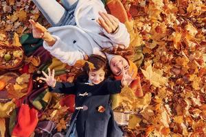 superiore Visualizza. posa giù su il terra. madre con sua poco figlia è avendo camminare nel il autunno parco foto