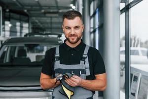 asciugandosi mani. uomo nel uniforme è Lavorando nel il autosalone a giorno foto