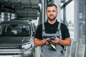 asciugandosi mani. uomo nel uniforme è Lavorando nel il autosalone a giorno foto