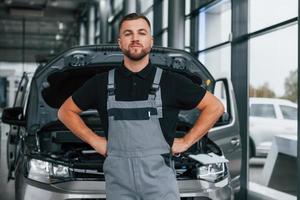 in piedi contro macchina. uomo nel uniforme è Lavorando nel il autosalone a giorno foto