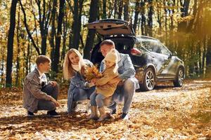 auto è dietro. contento famiglia è nel il parco a autunno tempo insieme foto