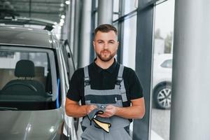 utensili nel mani. uomo nel uniforme è Lavorando nel il autosalone a giorno foto