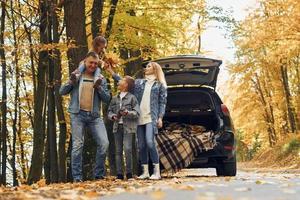 auto è dietro. contento famiglia è nel il parco a autunno tempo insieme foto