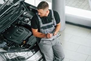 motore riparazione. uomo nel uniforme è Lavorando nel il autosalone a giorno foto