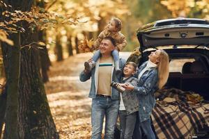 vicino auto con Aperto tronco. contento famiglia è nel il parco a autunno tempo insieme foto