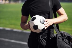 calcio giocatore su il campo. allegro giovane tipo nel nero camicia e pantaloni all'aperto a giorno foto