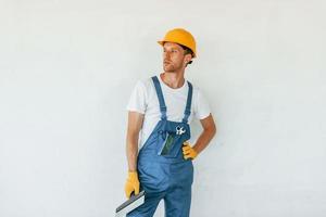 in posa per il telecamera. giovane uomo Lavorando nel uniforme a costruzione a giorno foto