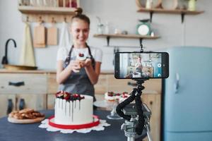 donna fa delizioso dolci e torta. registrazione processi di smartphone su tripode foto