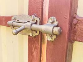 serratura su il porta nel il vecchio Casa. chiavistello a partire dal altro persone iscrizione. fatti in casa catenaccio su il porta e cancello di rosso colore. calcestruzzo box auto chiavistello foto