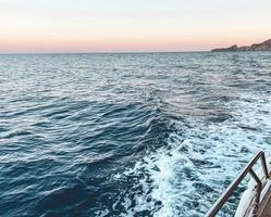camminare su il Aperto mare. blu onde di il mare su il sfondo di il tramonto. il yacht è attrezzata con metallo lati per il sicurezza di turisti. vacanze nel caldo paesi foto