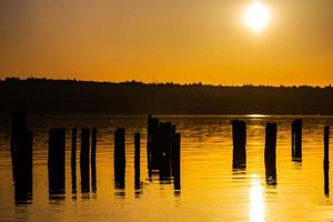 un' d'oro Alba al di sopra di un' collina riflettendo su acqua foto