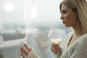 attraente bionda donne potabile vino di un' finestra. foto