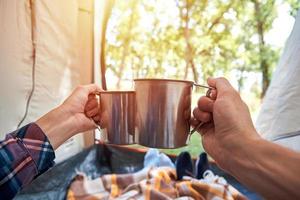 Due persone bevanda tè a partire dal un' tazze nel campeggio tenda foto