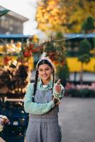 contadino donna nel denim tuta da lavoro sorridente Cordiali saluti mostrando pollice su. foto