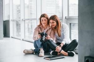 Due donne seduta in casa insieme e sembra a fotografie su il telecamera