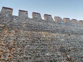 grande pietra parete di un vecchio antico medievale fortezza fatto di ciottoli contro un' blu cielo foto