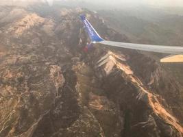 il aereo mosche a un' grande altezza al di sopra di il montagne e nebbia. il coda di il aereo è visibile nel il finestra. aria viaggio per un altro straniero nazione foto