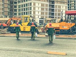 lavoratori nel arancia caschi e protettivo uniformi siamo su il costruzione luogo. costruzione di un' nuovo microdistretto nel il città centro. protettivo capi di abbigliamento per lavoratori foto