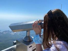 il ragazza sembra a il montagne e il cielo a partire dal un' grande fortezza parete nel il città di antalya nel tacchino. esso usi un' monoculare, un' telescopio, binocolo e Questo servizio è pagato foto