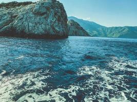 roccia nel il centro di il mare. blu acqua con spumeggiante schiuma con un' di grandi dimensioni, alto montagna nel il centro. sabbioso rocce. vacanza nel un' caldo nazione foto