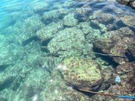 riva del mare con acqua e sabbia. un' enorme pietra affondò nel il acqua. il ancora di il nave riposa su esso. sottomarino mondo. acqua a il piede di il rocce foto