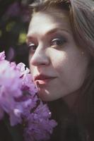 vicino su signora urgente guancia contro arbusto con rosa fiori ritratto immagine foto