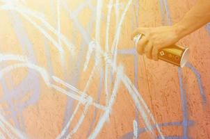 un' mano con un' spray può quello disegna un' nuovo graffiti su il parete. foto di il processi di disegno un' graffiti su un' di legno parete avvicinamento. il concetto di strada arte e illegale vandalismo