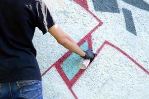 un' giovane teppista vernici graffiti su un' calcestruzzo parete. illegale vandalismo concetto. strada arte foto