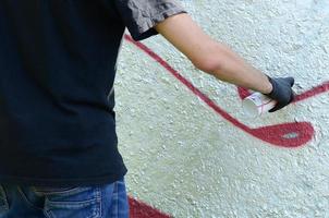 un' giovane teppista vernici graffiti su un' calcestruzzo parete. illegale vandalismo concetto. strada arte foto