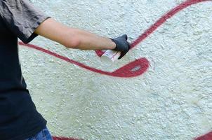 un' mano nel nero guanti vernici graffiti su un' calcestruzzo parete. illegale vandalismo concetto. strada arte foto