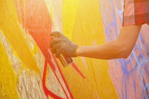 un' mano con un' spray può quello disegna un' nuovo graffiti su il parete. foto di il processi di disegno un' graffiti su un' di legno parete avvicinamento. il concetto di strada arte e illegale vandalismo