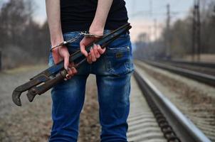 il ragazza nel manette con il tubo chiave inglese su il ferrovia traccia foto