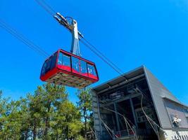 rosso moderno turista cabina di il cavo auto ascende il montagne contro il blu cielo foto