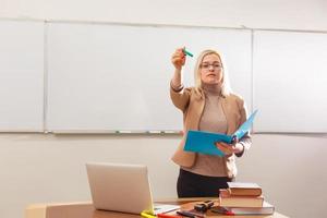 ritratto di bella insegnante Tenere taccuini nel un' aula nel scuola foto