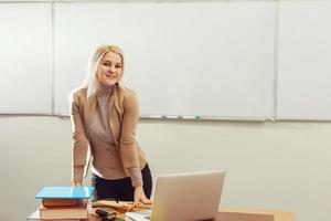 bella insegnante sorridente a telecamera a indietro di aula a il elementare scuola foto