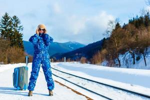 giovane donna nel inverno Abiti in attesa per sua treno foto