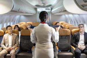 l'assistente di volo asiatico sta dimostrando la procedura di sicurezza utilizzando la cintura di sicurezza prima di decollare in aereo per l'equipaggio di cabina e il concetto di business della compagnia aerea foto