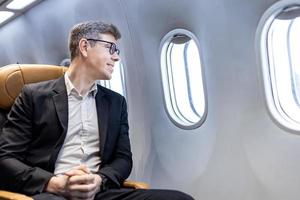 caucasico uomo d'affari è in viaggio e seduta comodamente nel il aereo mentre guardare su il finestra per attività commerciale viaggio nel economia classe posto a sedere foto