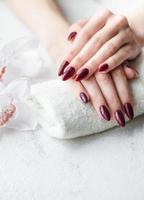 mani di un' giovane donna con buio rosso manicure su Chiodi foto